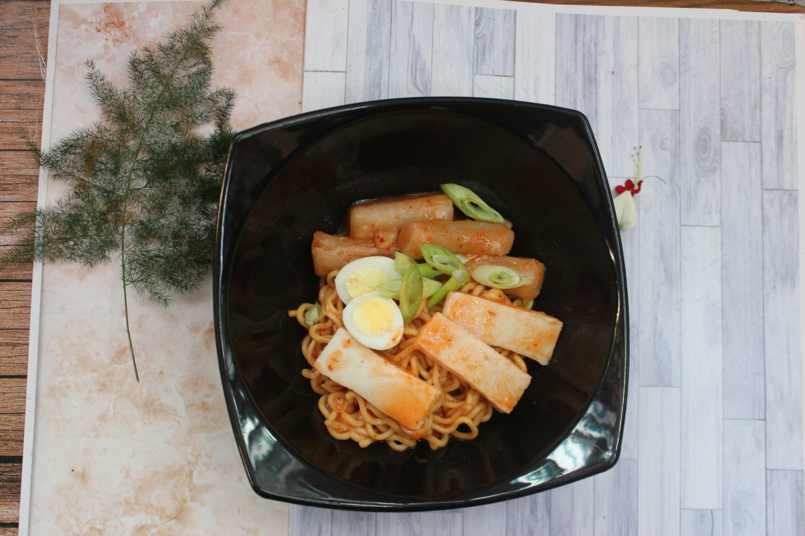 a black bowl filled with noodles and vegetables